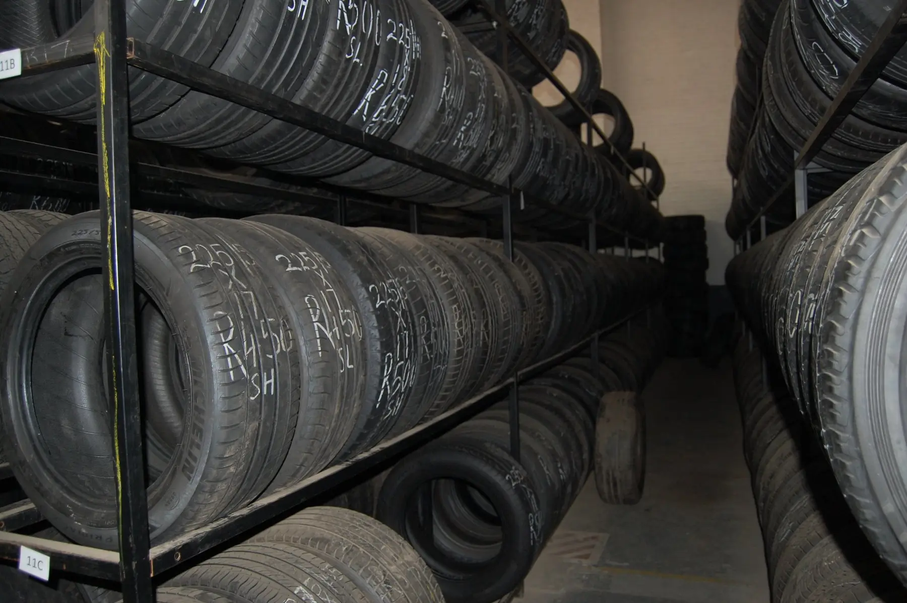Aisle between floor-to-ceiling racks of used tyres, each marked in chalk with its size